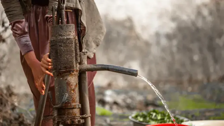 Hand pump delivering clean water into a bucket in a rural village